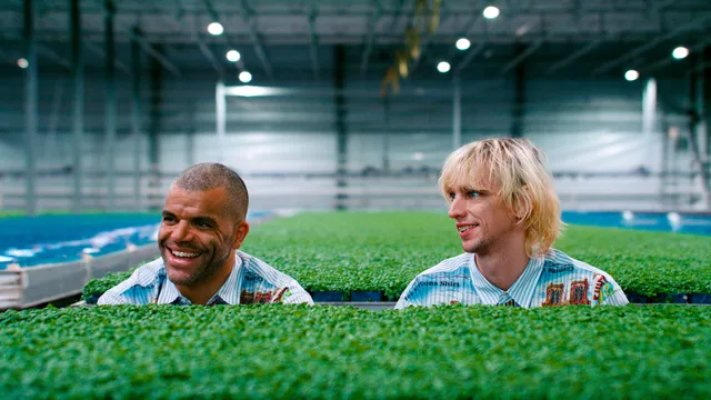 Yousef Gnaoui en Pepijn Lanen kijken naar links terwijl ze in een hal zijn met veel kleine groene plantjes.