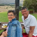 Reino en Joop zitten samen aan een tafel en lachen naar de camera.