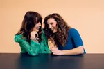 Twee vrouwen, Brankele Frank en Malou Holshuijsen, met bruine haren kijkend schaterlachend naar elkaar