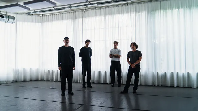 De band Docile Bodies poseert voor een raam en gordijn
