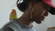 Vrouw met parkiet op haar schouder kijkt naar beneden