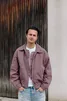 Jongen met rode jas voor houten wand