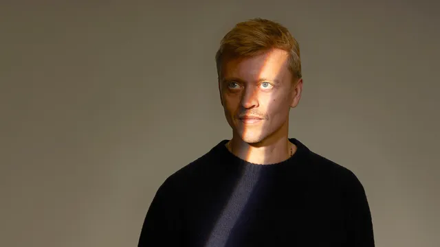 Nicolaas kijkt opzij. Er valt een streep licht op zijn gezicht.