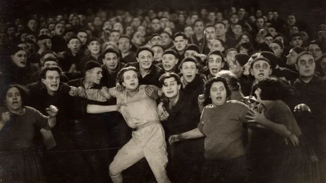 Een groep mensen die elkaar vasthoudt en geschrokken in de camera kijkt