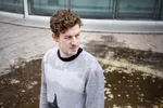 Lucas Derycke kijkt opzij. Hij heeft een grijze sweater aan.