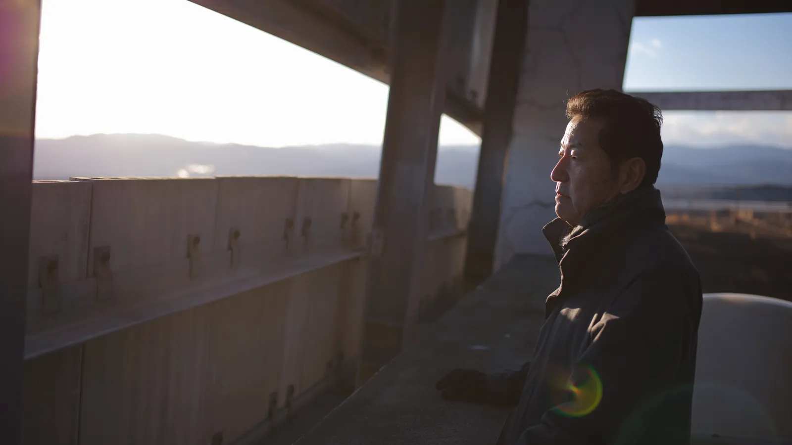 Man die vanuit een gebouw met een treurige uitstraling naar buiten kijkt.