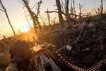 Point of view beeld van een soldaat met een geweer die schiet in een bos waar nog weinig van over lijkt te zijn.