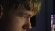 Een close up van het gezicht van een jongen waarbij het licht van een scherm in zijn gezicht schijnt.