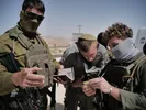 Drie soldaten van het Israëlische leger (IDF) voeren een paspoortcontrole uit op de Westelijke Jordaanoever. Twee van hen zijn onherkenbaar, de middelste man heeft geen gezichtsbedekking en draagt een keppeltje. De sfeer is vijandig.
