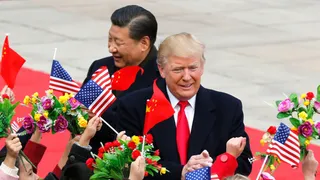 De president van de Verenigde Staten en de partijleider van China lopen tussen kinderen die Chinese en Amerikaanse vlaggetjes en bloemen omhooghouden.