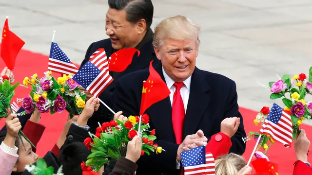 De president van de Verenigde Staten en de partijleider van China lopen tussen kinderen die Chinese en Amerikaanse vlaggetjes en bloemen omhooghouden.