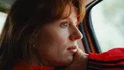Een vrouw zit in de auto en kijkt uit het raam.