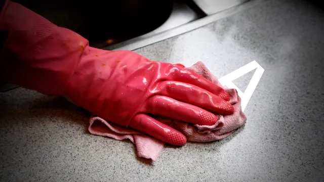 Foto van een hand die met een schoonmaakdoek over een aanrechtblad gaat.