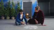 Twee mensen zitten op de grond, ze spelen met stoepkrijt