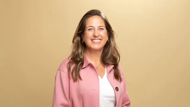 Marjolein Moorman met een roze jasje vanaf middel voor een gele achtergrond