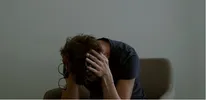 Iemand zit met de handen over de oren naar beneden te kijken.