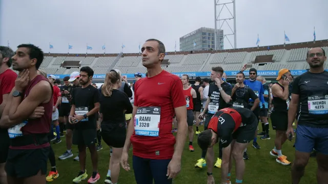 Een renner in een rood shirt staat bij de start en kijkt in de verte.