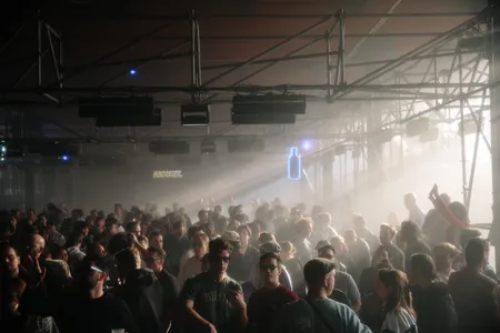 Mensen in een donkere loods waar licht door de ramen naar binnen schijnt