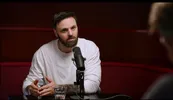 Tim Hofman is te gast in de podcast, hij heeft een microfoon voor zich