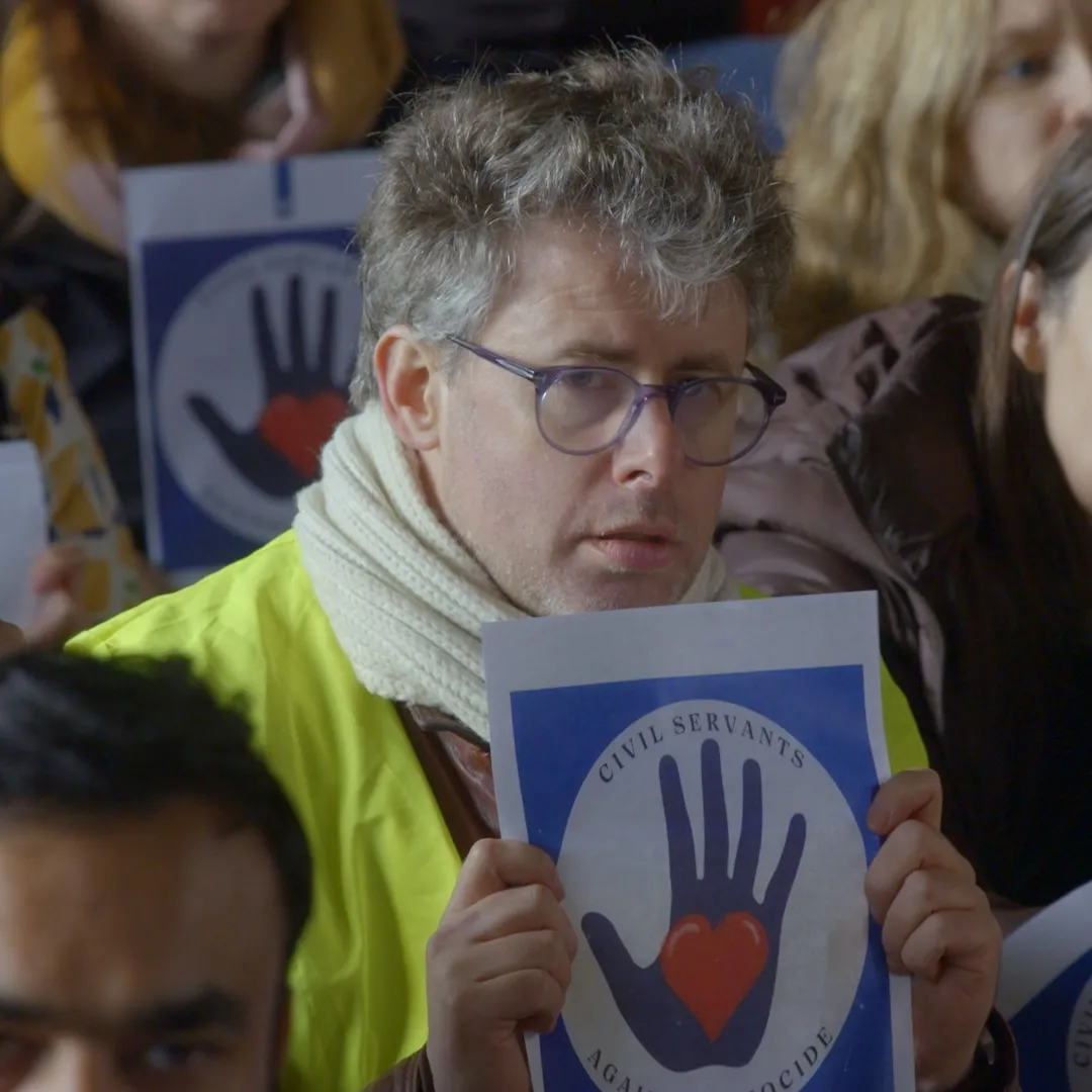 Een groep demonstranten waar een deel ervan zit en een andere deel ervan staat ze hebben protestbordjes bij zich.