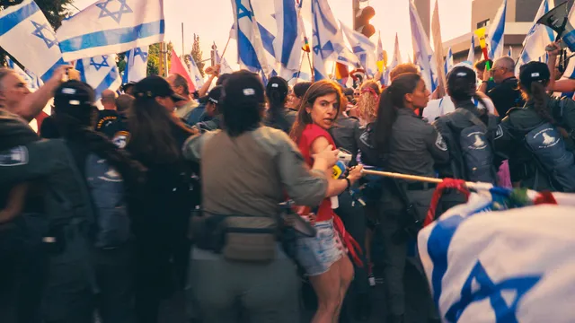 Nava Rozolio, een protestleider, wordt tijdens een demonstratie in Jeruzalem door een politieagent geduwd.