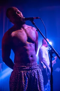 De zanger van Ploegendienst met ontbloot bovenlichaam waardoor zijn vele tatoeages zichtbaar zijn