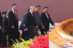 Drie wereldleiders, Poetin, Xi en Kim Jong Un, lopen een trap op in Peking. Ze lachen
