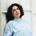 Asefeh Eskandari staat tegen een witte achtergrond, ze draagt een blauwe blouse.