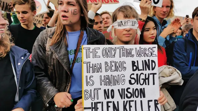 Een aantal mensen in een demonstratie. Op het protestbord staat: "The only thing worse than being blind is having sight but no vision - Helen Keller"