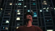Pete staat voor een gebouw en kijkt naar boven, het is al donker