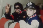 Links Michael Jackson, een man met zwarte krullen die het peace-teken doet naar de camera en rechts een kind met een zwarte pet.