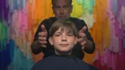 Leonid zit in de kappersstoel met een kleine glimlach