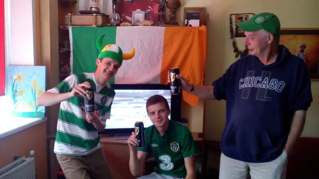 Ierse supporters voor de wedstrijd in gedecoreerde woonkamer poseren met een halte liter bier