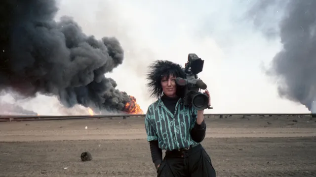 Foto van Margaret Moth met een camera op haar schouder met op de achtergrond een brand