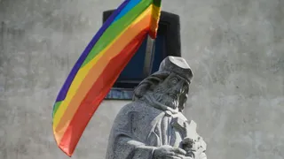 Religieus stenen standbeeld met regenboogvlag erachter