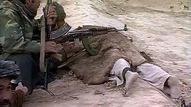 Een soldaat van de Noordelijke Alliantie gebruikt het lijk van een overleden Taliban-strijder als steun voor zijn geweer.