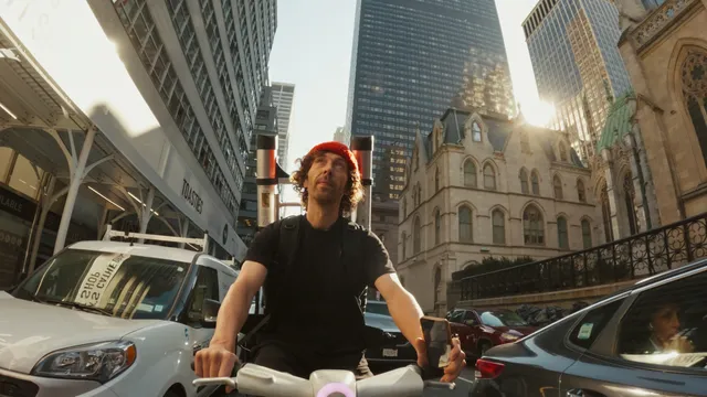 Een man op een scooter met een rode muts rijdt door een drukke stad, New York.