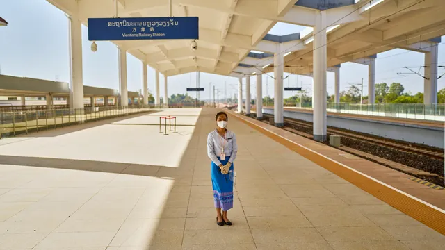 De wereld van de Chinezen, Een vrouw staat in het gelid op het gloednieuwe perron van het treinstation van Vientiane, de hoofdstad van Laos. Het land is een eerste stop op China’s Nieuwe Zijderoute en het spoor werd aangelegd door een Chinees staatsbedrijf.