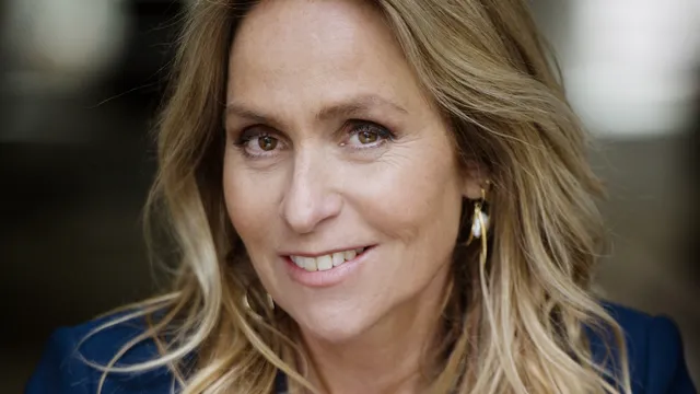 Esther is een blonde vrouw met bruine ogen, ze kijkt in de camera
