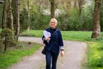 Britta loopt buiten met papieren in haar handen, ze glimlacht