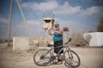 Christelijke man op een fiets voor het hek naar Gaza