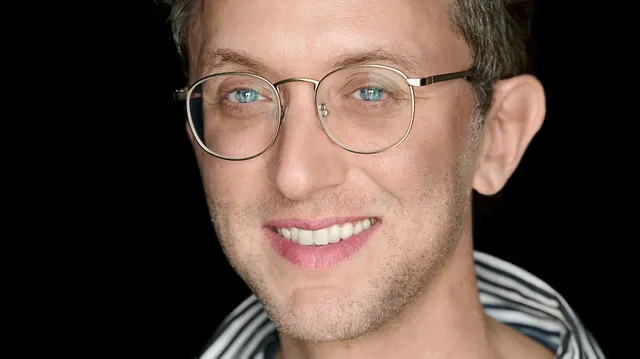 Portret van regisseur David Borenstein: man met krullen, blauwe ogen, bril en gestreept overhemd