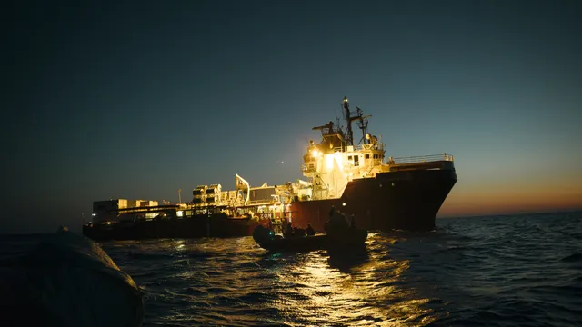 Een groot reddingsschip 's nachts op zee, met een kleine reddingsboot op de voorgrond.