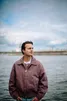 Jongen met rode jas op de kade, voor het water