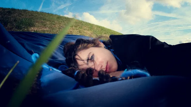 maryn Charlie ligt in het gras tussen blauwe draden