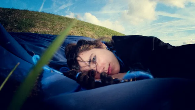 maryn Charlie ligt in het gras tussen blauwe draden