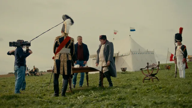 Filmcrew filmt Napoleontische scène op grasveld met witte tent.
