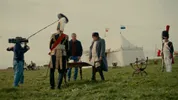Filmcrew filmt Napoleontische scène op grasveld met witte tent.