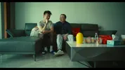 Pete zit op de bank met zijn vader, ze lachen met elkaar.