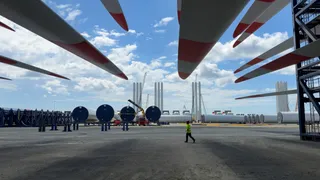 Een windmolenpark in aanbouw met grote windturbineonderdelen op een industrieterrein.